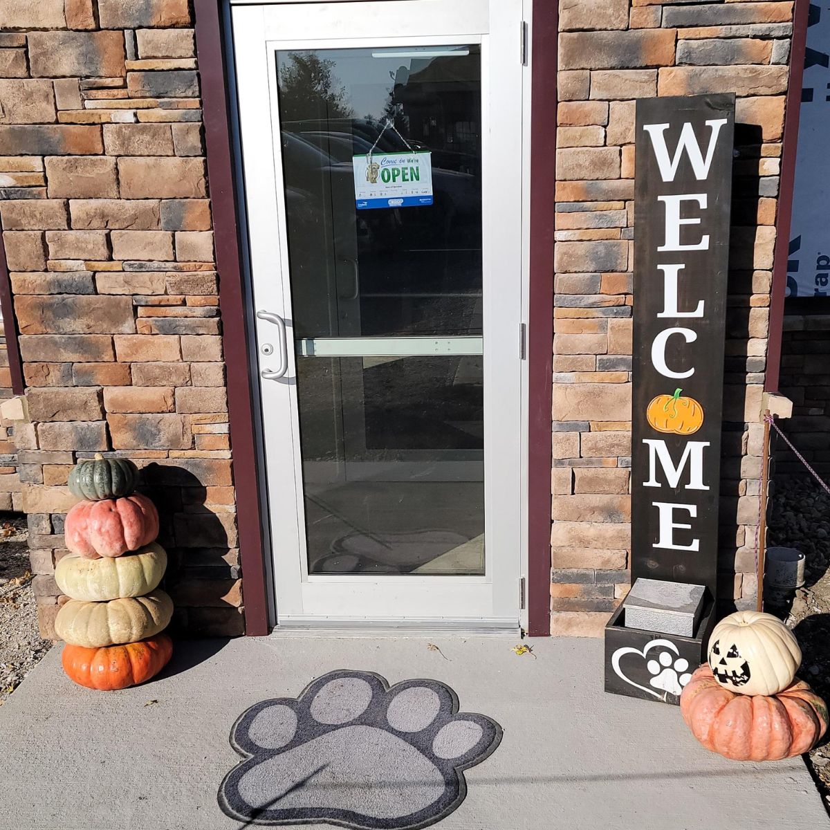 a welcome sign with a dog's paw and pumpkins